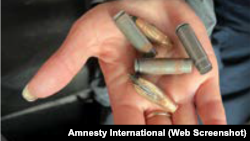 Жена Евгения Петрашенко держит пули и гильзы, найденные в доме в Буче, где убили Евгения Петрашенко. Фото Amnesty International из отчета "Он не вернется". Военные преступления в северо-западных районах Киевской области